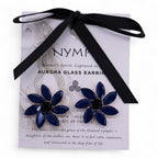 Navy blue flower earrings on a white card with black ribbon, featuring the brand 'NYMP'.