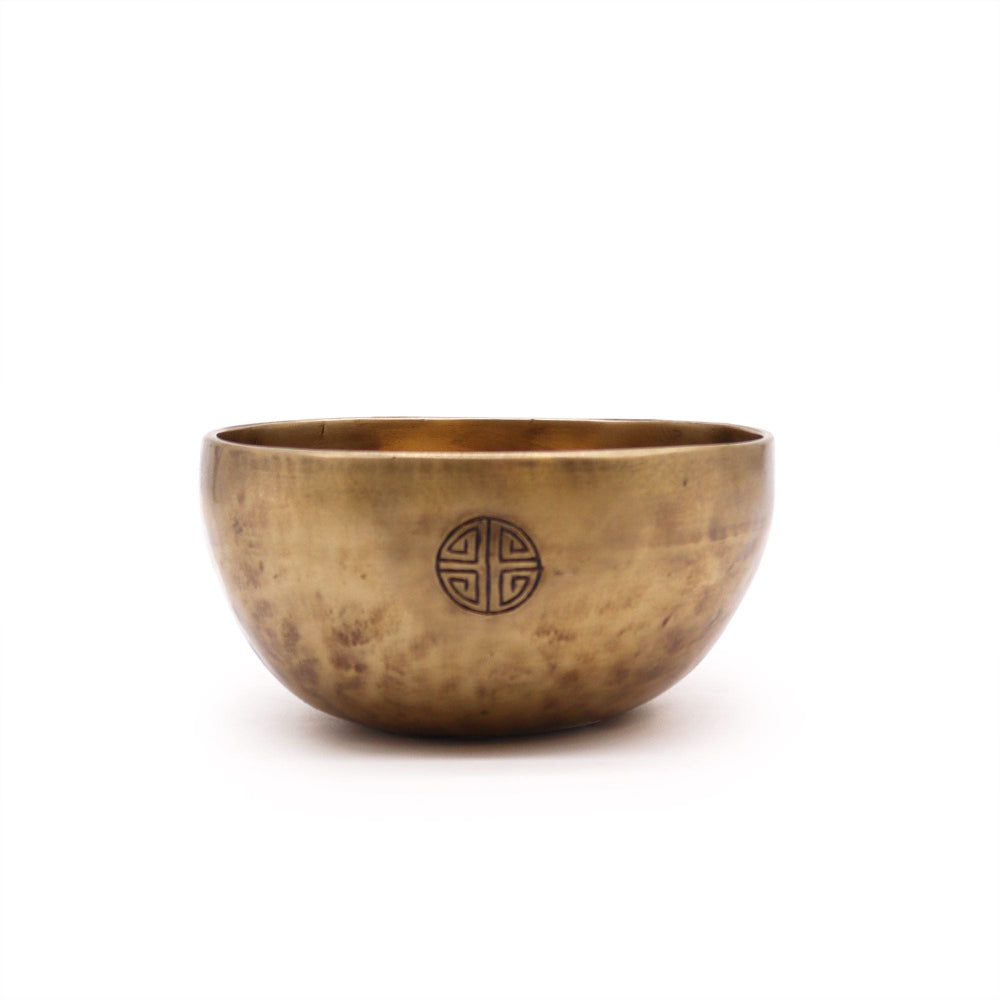 Bronze singing bowl with a circular emblem on a white background