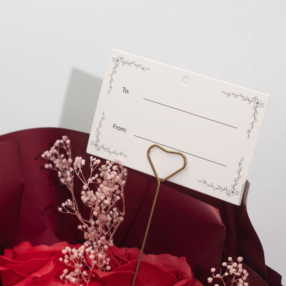 Gift tag with 'To' and 'From:' fields on a red fabric background with dried flowers.