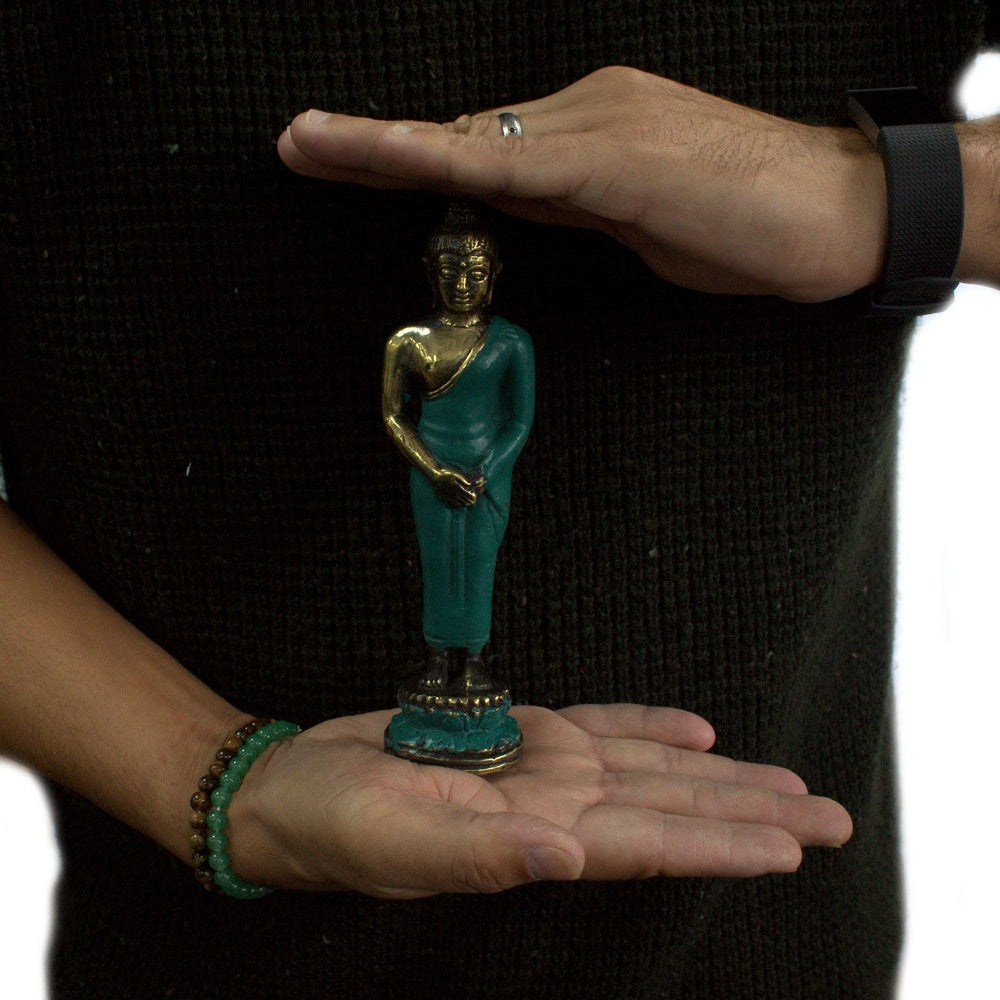 Person holding a small turquoise Buddha statue between their palms.