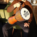 Person holding a drum with 'Freedom Rhythm' branding in an indoor setting.