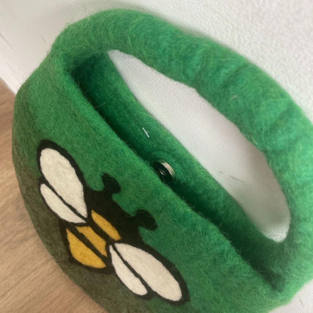 Green slippers with a bee design on a white background