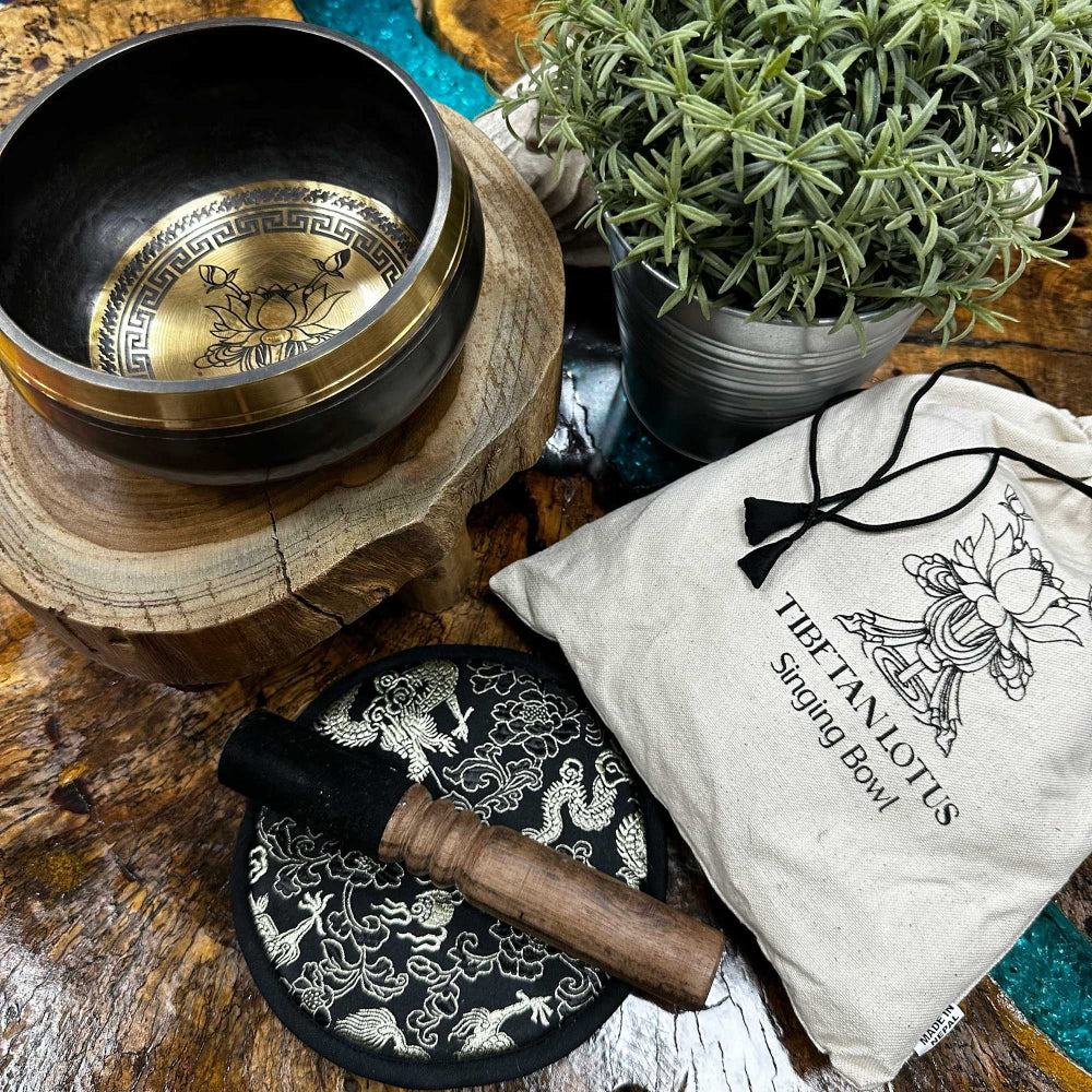 Tibetan singing bowl set with wooden mallet and pouch on a wooden surface.