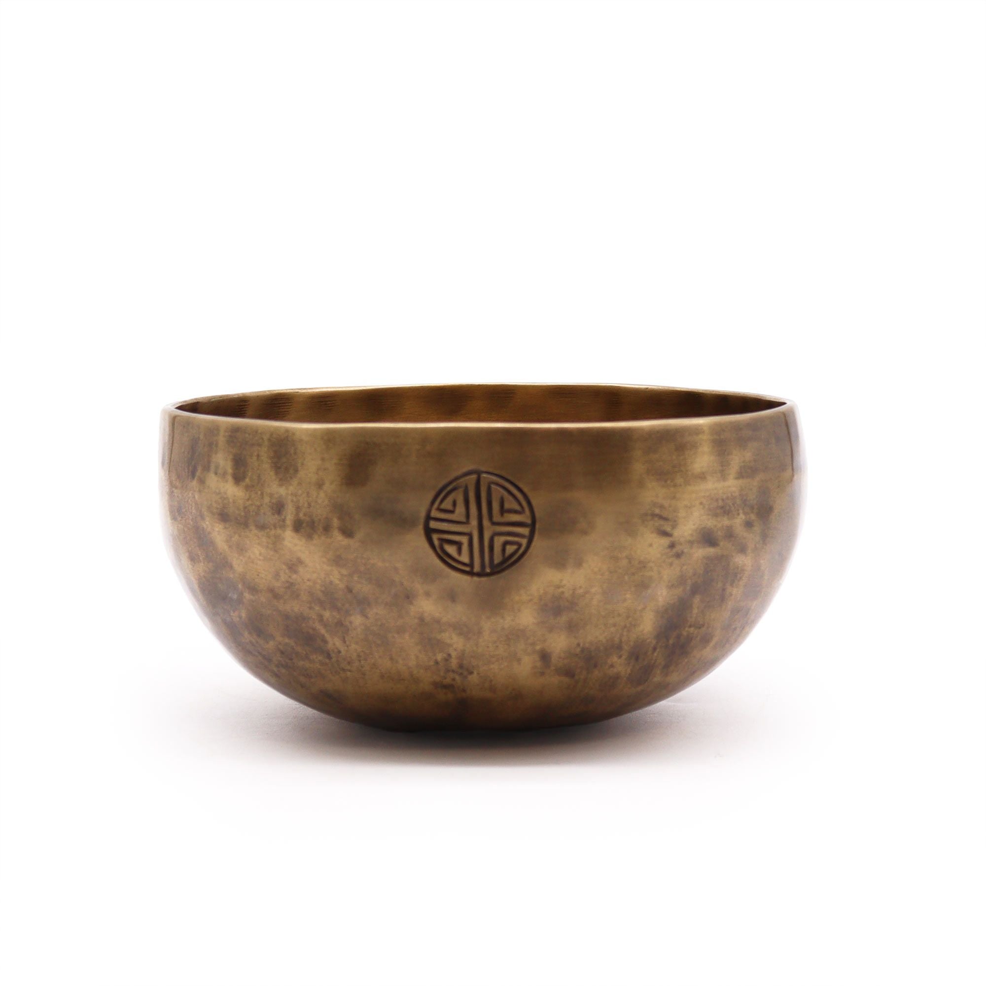 Bronze singing bowl with a circular emblem on a white background