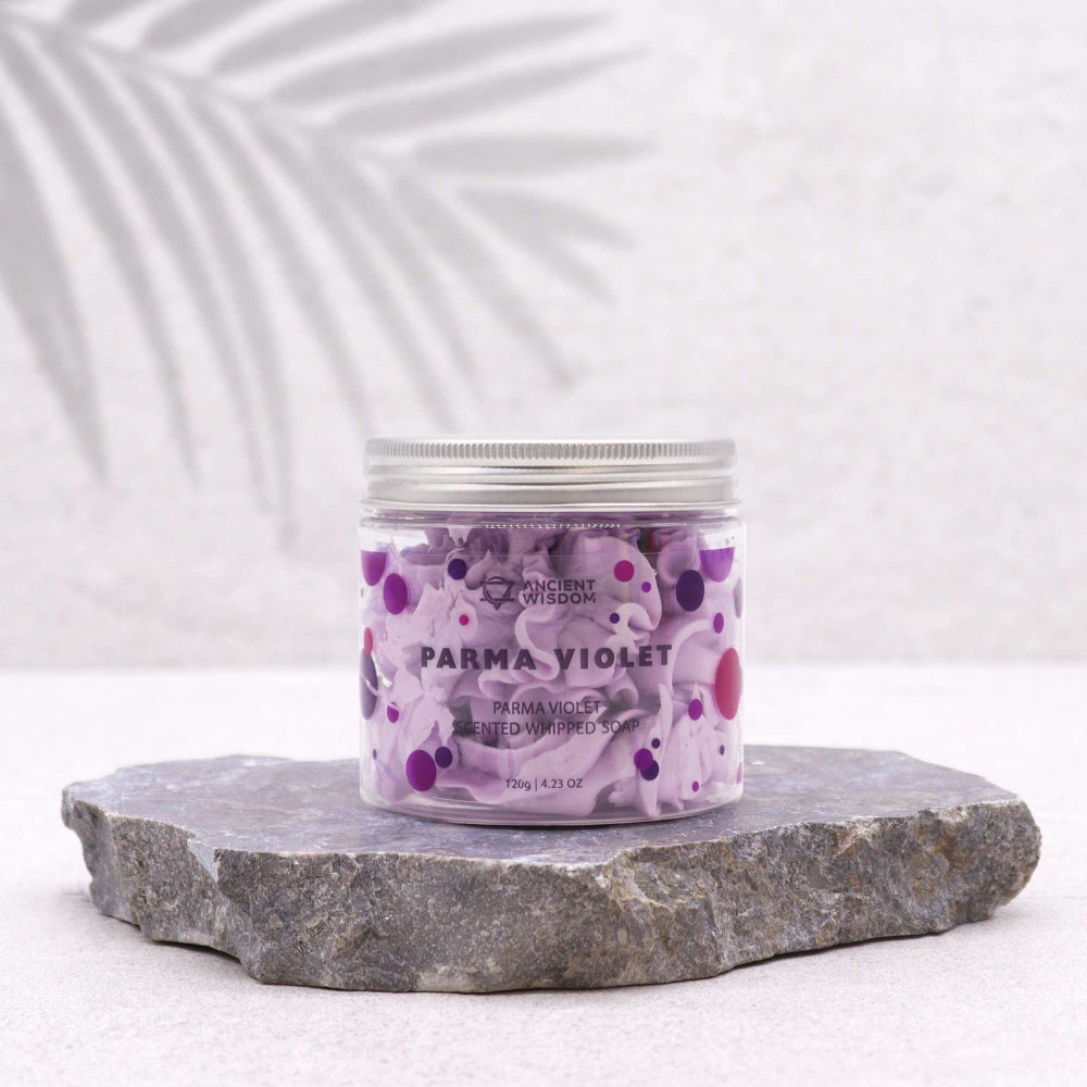 Jar of Parma Violet body scrub on a stone surface with a white background