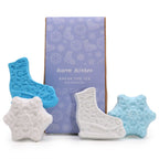 Set of bath bombs shaped like ice skates and snowflakes with a branded box on a white background.