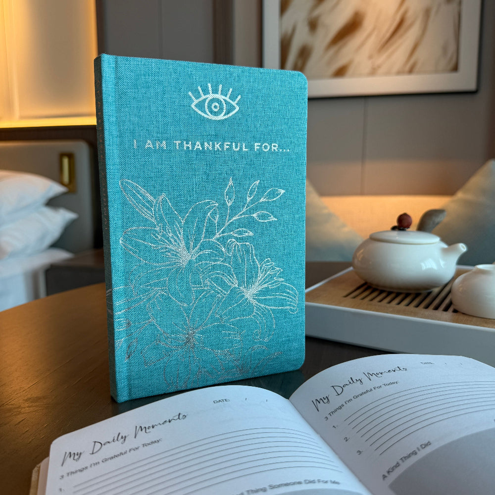 Turquoise gratitude journal with floral design on a table with tea set