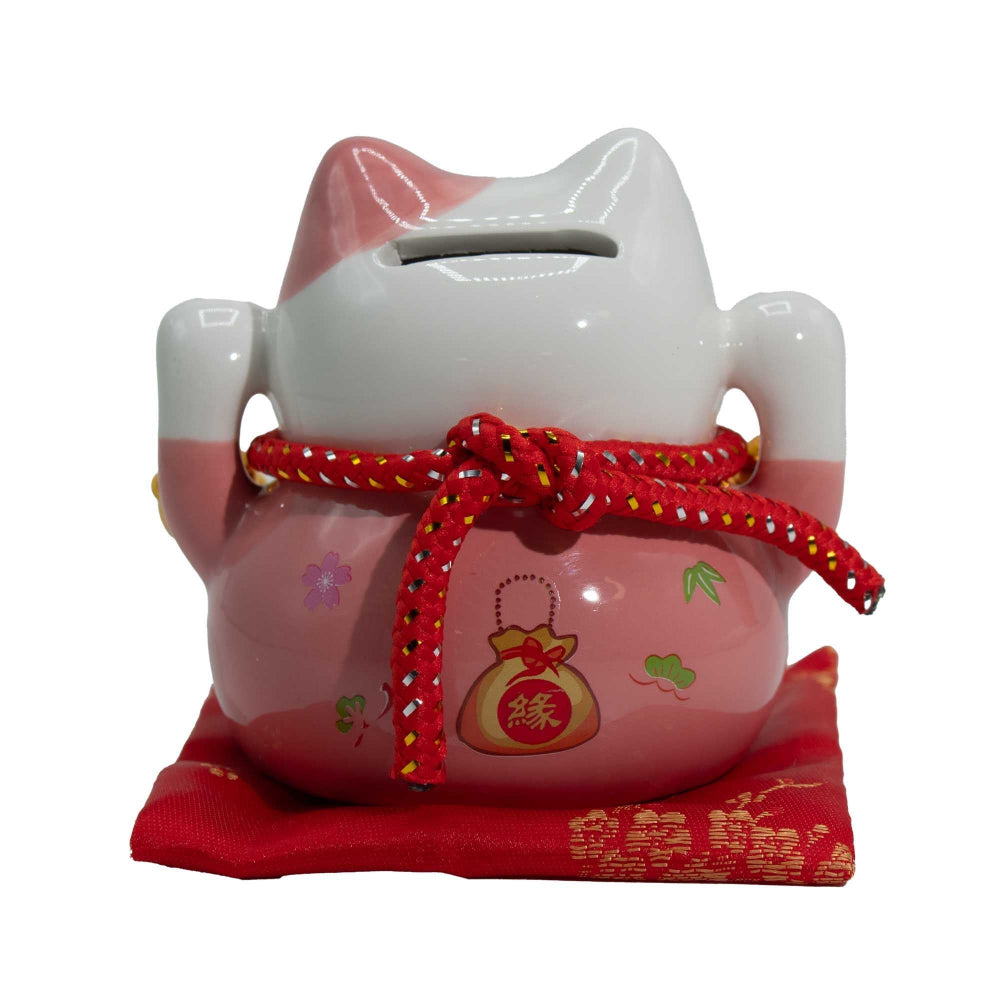 Pink and white cat-shaped money box with red string and pouch on a white background