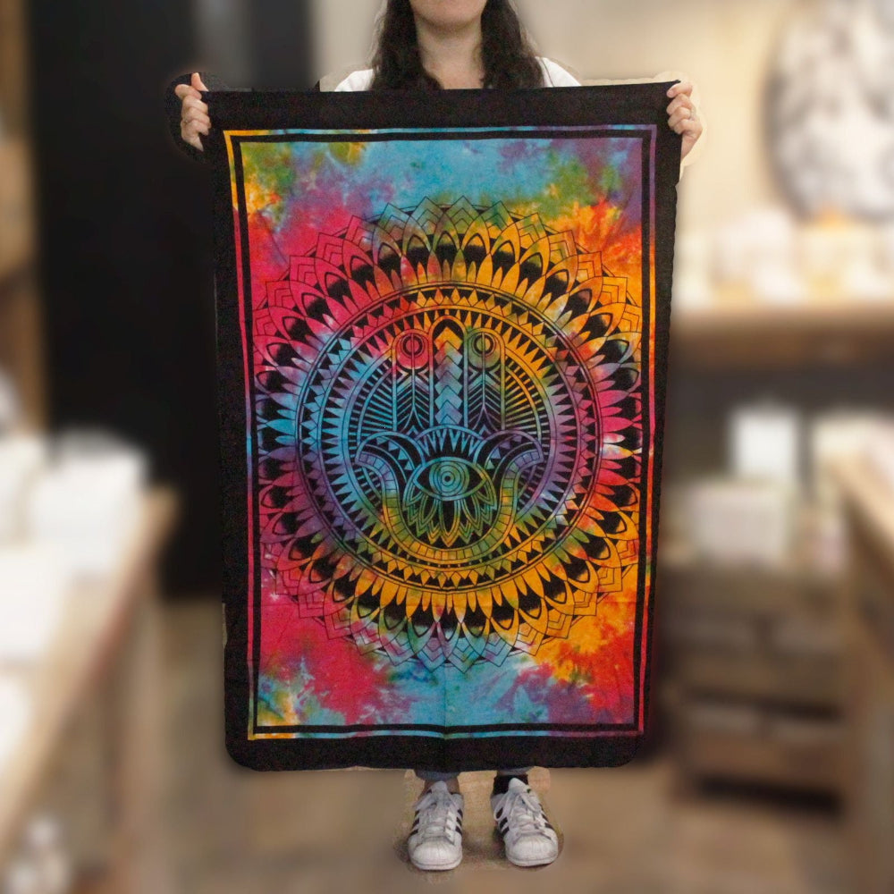 Person holding a colorful tapestry with a vibrant design