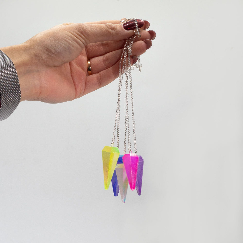 Hand holding a necklace with colorful pendant against a white background