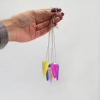 Hand holding a necklace with colorful pendant against a white background