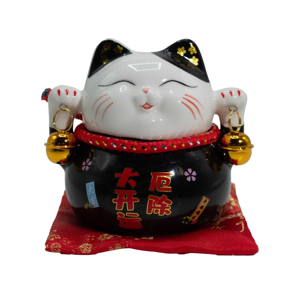 Maneki-neko cat figurine with black and white face, red collar, and gold bells on a white background.