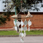 Decorative fish-shaped wind chime with shell-like beads hanging outdoors.