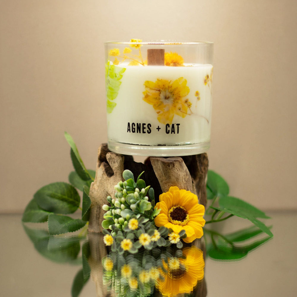 Candle with floral design on a wooden stand with plants around