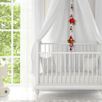 White crib with canopy and hanging gnome decorations in a bright room with large windows.