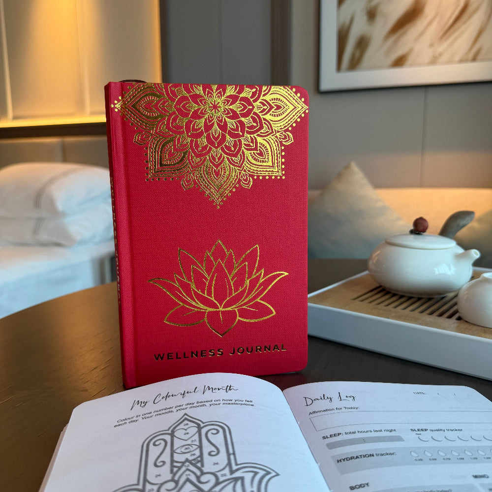 Red wellness journal with gold designs on a table with tea set