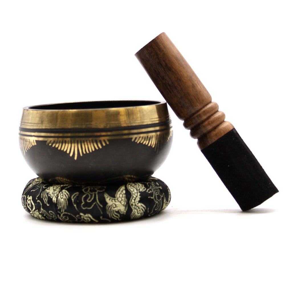 Black singing bowl with gold accents and wooden striker on a white background