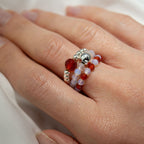 Close-up of a hand wearing multiple beaded rings with a plain background