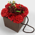 Bouquet of red soap flowers   in a brown paper bag with a string handle on a white background