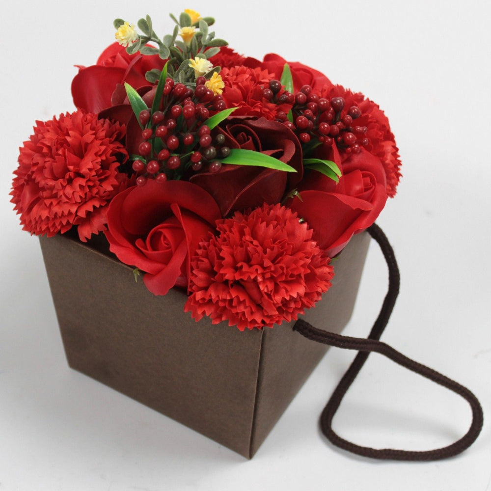 Bouquet of red soap flowers   in a brown paper bag with a string handle on a white background