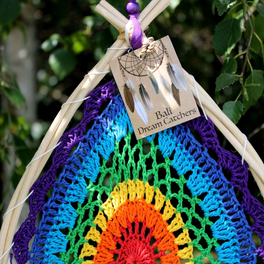Colorful dreamcatcher with a 'Bali Dream Catchers' tag against a natural background.