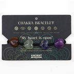 Chakra bracelet with heart-shaped stones on a black card with text and symbols.