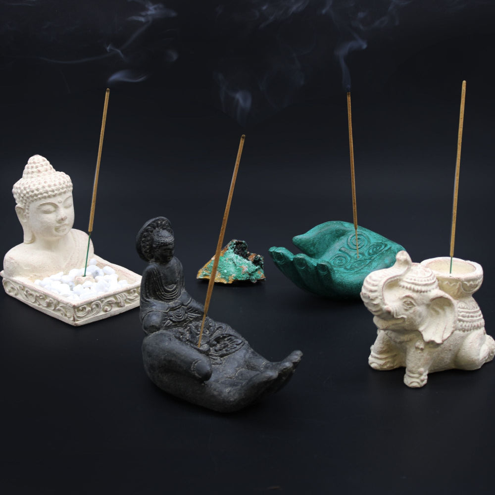 Collection of incense holders with incense sticks on a dark background