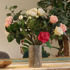 Bouquet of pink, white, and red flowers in a textured silver vase on a wooden table.