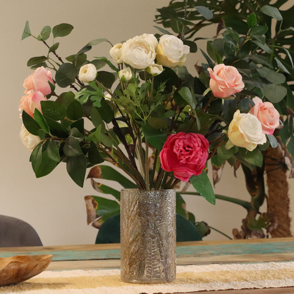 Bouquet of pink, white, and red flowers in a textured silver vase on a wooden table.