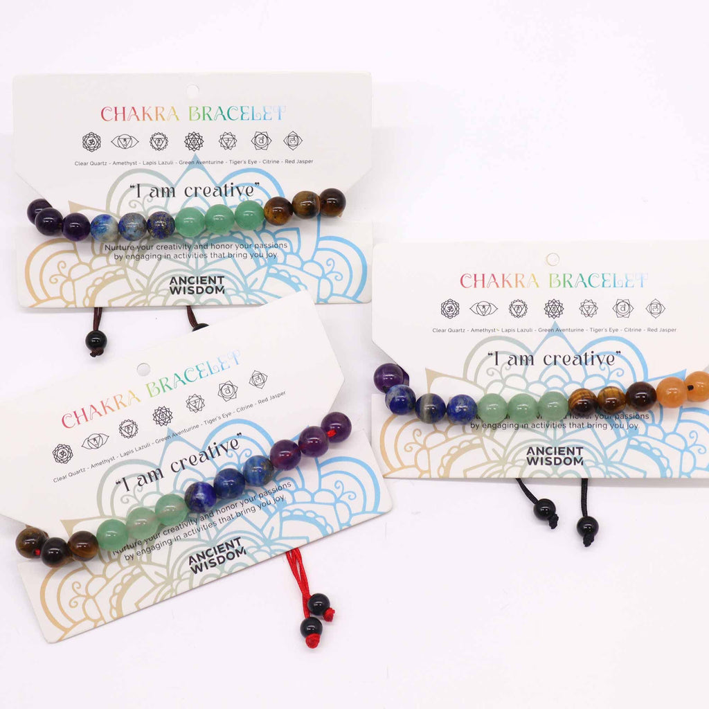 Chakra bracelets on display with their packaging on a white background