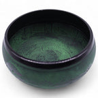 Green singing bowl with intricate patterns on a white background