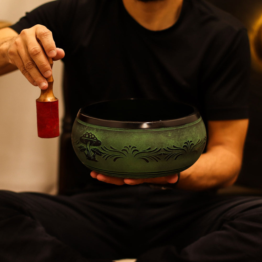 Person holding a green singing bowl with a decorative handle.