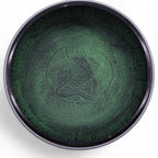 Decorative green dish with engraved design on a white background