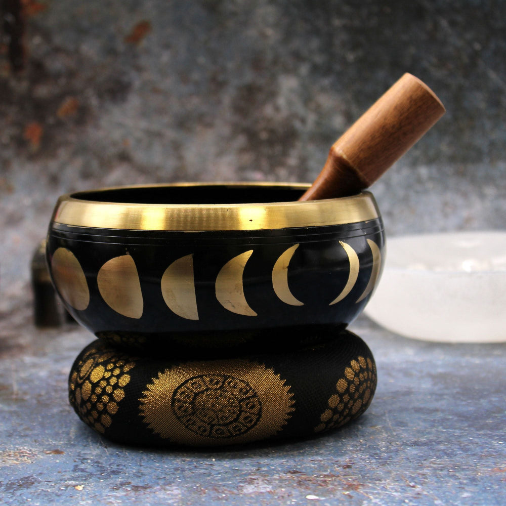 Black and gold decorative bowl with a wooden stick on a textured surface