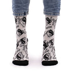 White socks with black cat illustrations worn by a person in blue jeans on a white background