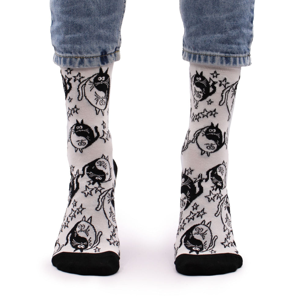 White socks with black cat illustrations worn by a person in blue jeans on a white background