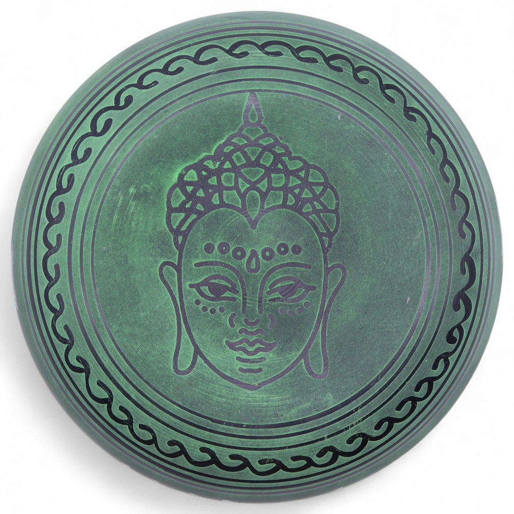 Decorative plate with Buddha face design on a green background