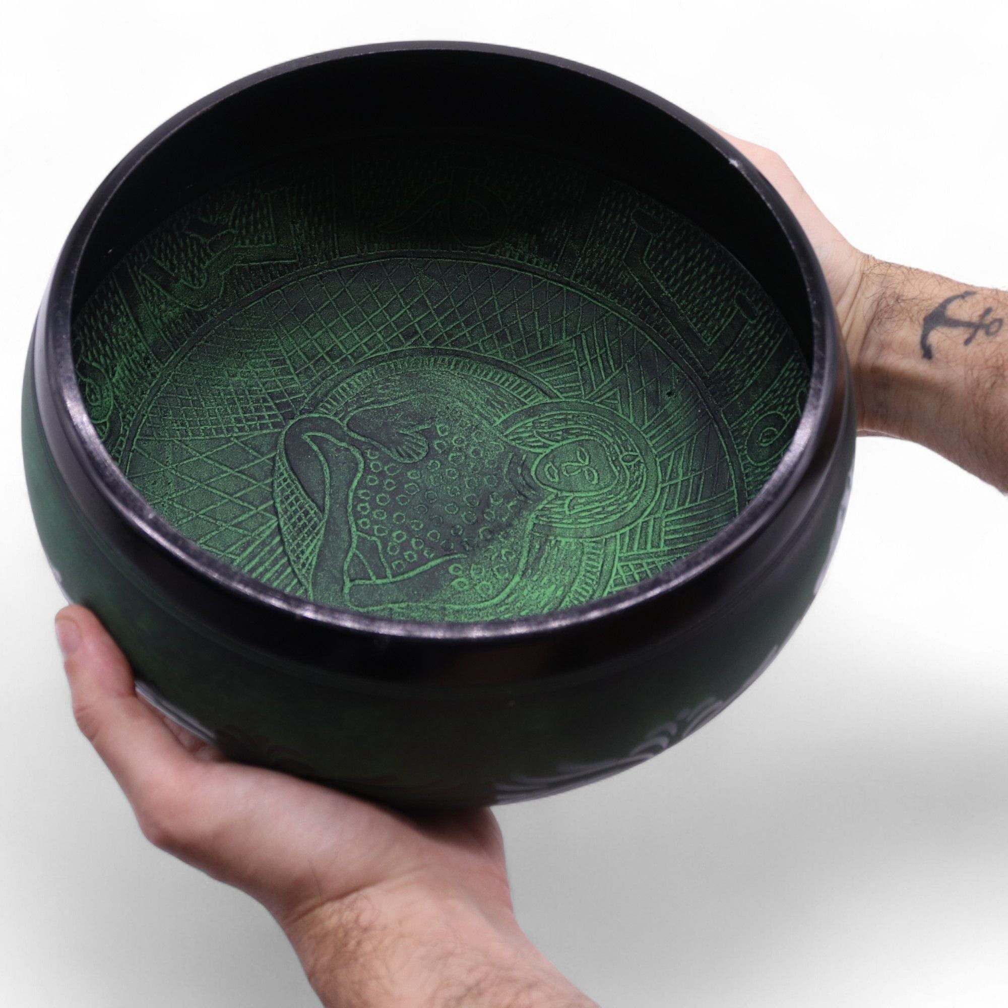 Black bowl with green interior design held by a hand on a white background