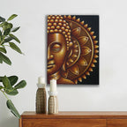 Decorative wall art of a Buddha face on a white wall above a wooden cabinet with candles and a plant.