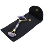 Amethyst facial roller on a black pouch with gold accents