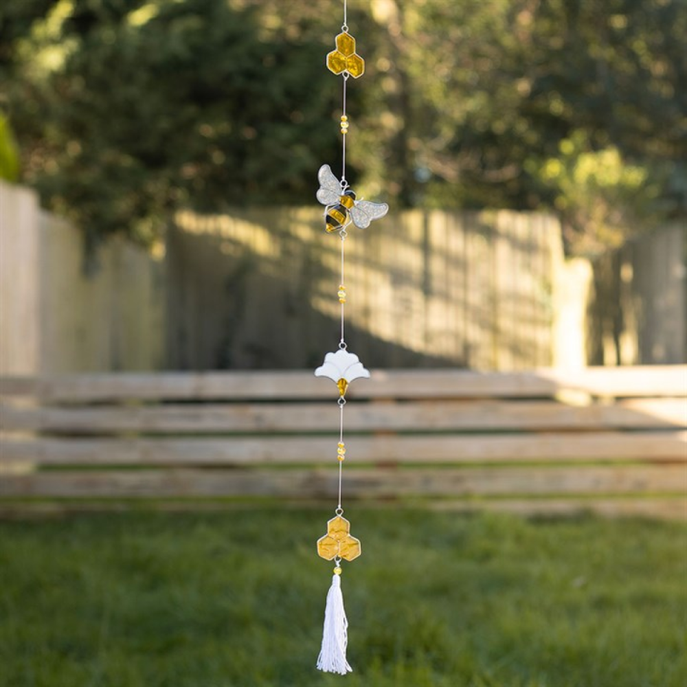 Decorative hanging chain with bees and tassels in a garden setting