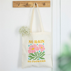 Tote bag with floral design and 'No Rain No Flowers' text hanging on a hook.
