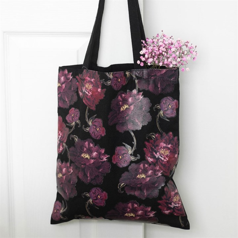 Black tote bag with purple floral pattern on a white background