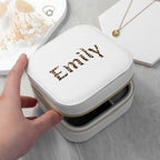 White jewelry case with 'EMILY' embroidery held by a hand on a light gray surface.