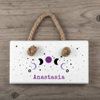 Decorative wall hanging with moon phases and the name 'Anastasia' on a light blue background.