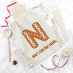 Baking-themed drawstring bag with gingerbread design and text, surrounded by baking tools on a marble surface.